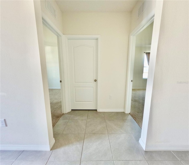 corridor with tile patterned flooring, carpet flooring, and visible vents