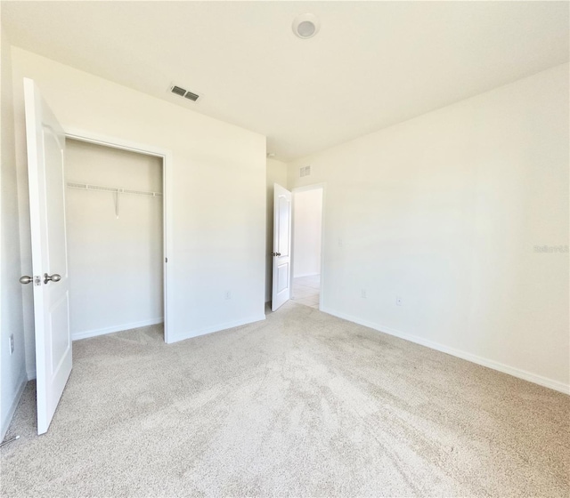 unfurnished bedroom featuring baseboards, visible vents, light carpet, and a closet