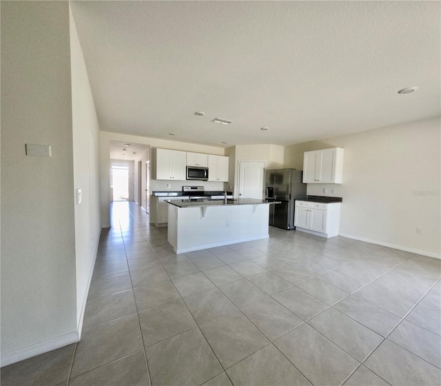 kitchen featuring a center island with sink, appliances with stainless steel finishes, white cabinetry, and baseboards