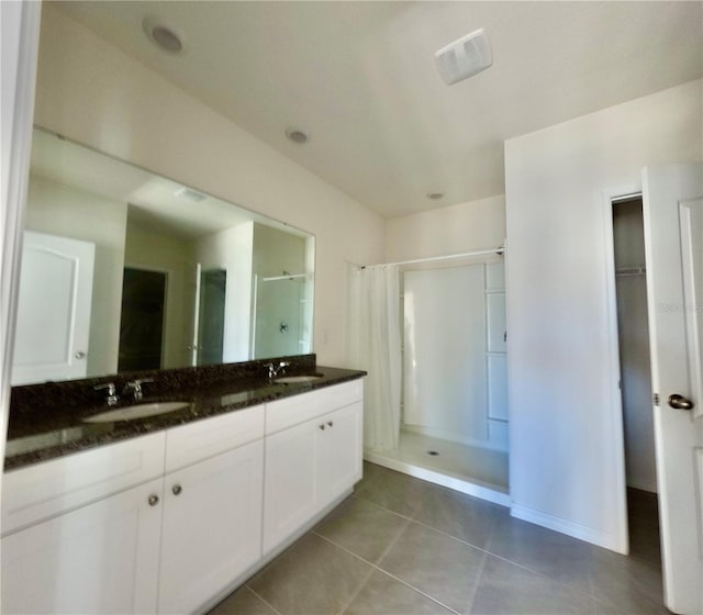 bathroom featuring visible vents, double vanity, a sink, a shower stall, and tile patterned floors