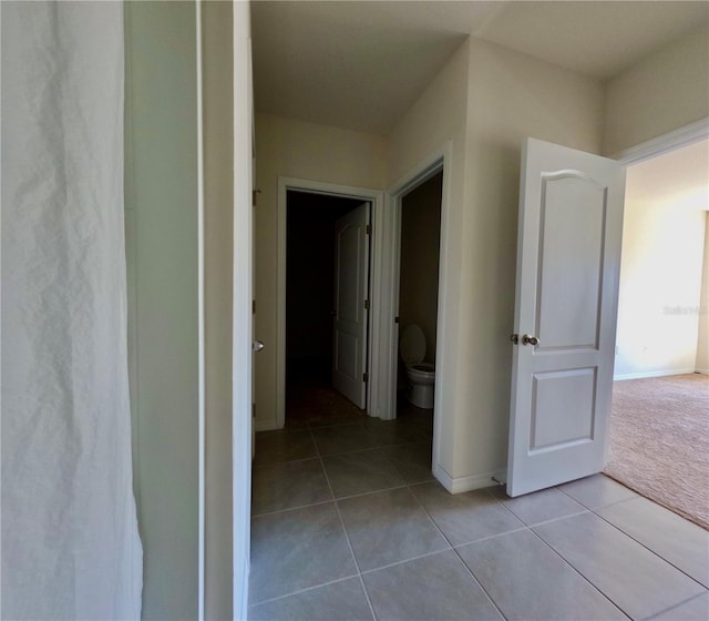 hall with tile patterned flooring, baseboards, and carpet floors