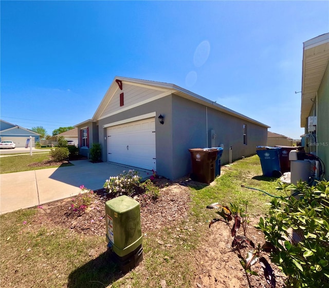 view of property exterior featuring stucco siding, concrete driveway, and a garage