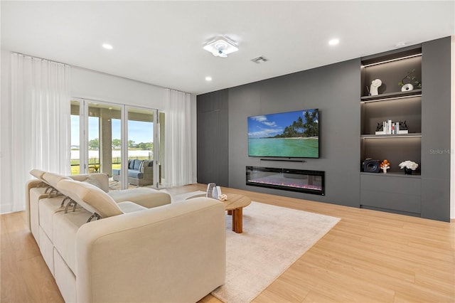 16689 Broadwater Ave, Winter Garden, FL 34787 - living room featuring a glass covered fireplace, wood finished floors, visible vents, and built in features