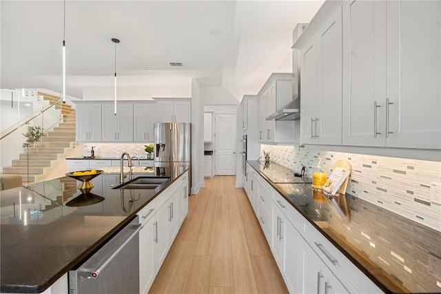 16689 Broadwater Ave, Winter Garden, FL 34787 - kitchen with wall chimney range hood, tasteful backsplash, a sink, light wood-style floors, and stainless steel appliances