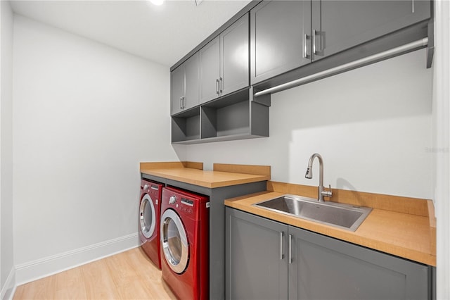 16689 Broadwater Ave, Winter Garden, FL 34787 - clothes washing area with a sink, light wood-type flooring, baseboards, separate washer and dryer, and cabinet space