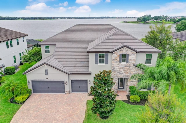 16689 Broadwater Ave, Winter Garden, FL 34787 - traditional-style house featuring a tiled roof, stone siding, a garage, stucco siding, and decorative driveway