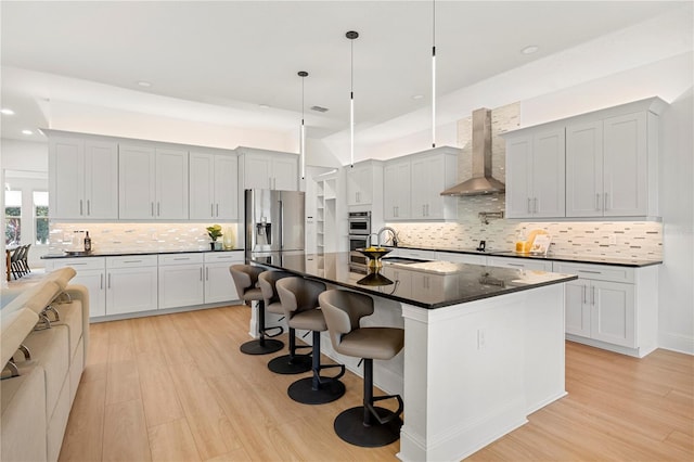 16689 Broadwater Ave, Winter Garden, FL 34787 - kitchen featuring wall chimney exhaust hood, stainless steel appliances, a sink, and light wood-type flooring