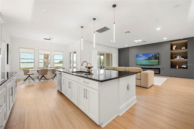 16689 Broadwater Ave, Winter Garden, FL 34787 - kitchen featuring dark countertops, light wood finished floors, white cabinets, pendant lighting, and an island with sink