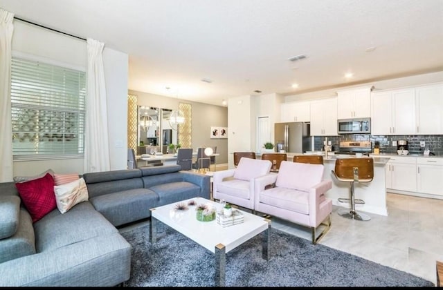 living area featuring an inviting chandelier, recessed lighting, a healthy amount of sunlight, and visible vents
