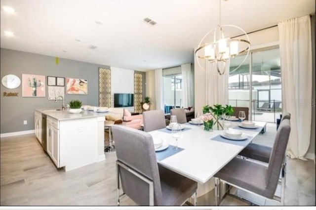dining space with an inviting chandelier, light wood-style floors, baseboards, and visible vents