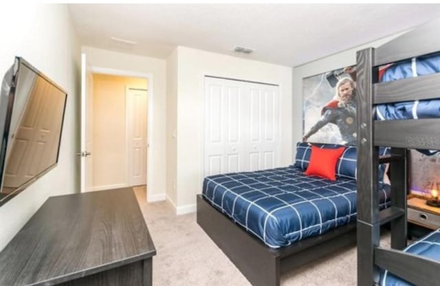 carpeted bedroom featuring baseboards and a closet