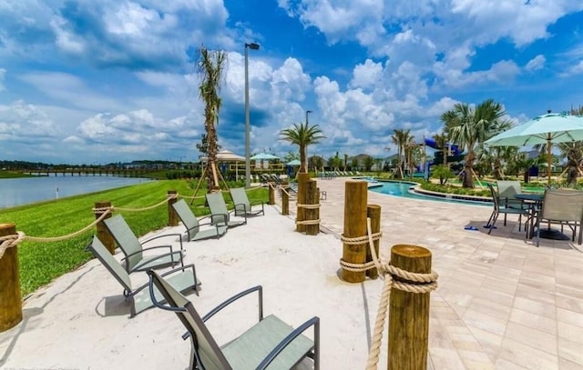 view of property's community with a pool, a patio, and a water view