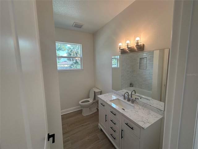 full bathroom featuring vanity, wood finished floors, visible vents, baseboards, and toilet