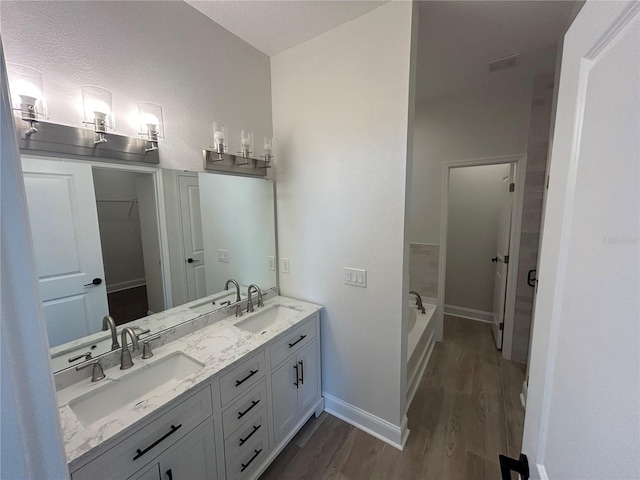 bathroom with double vanity, wood finished floors, baseboards, and a sink