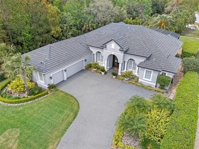 view of front of property with a garage, stucco siding, a front lawn, and driveway