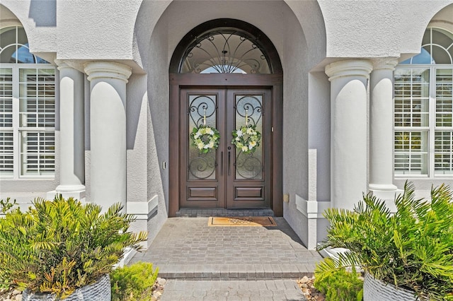 entrance to property featuring stucco siding and french doors