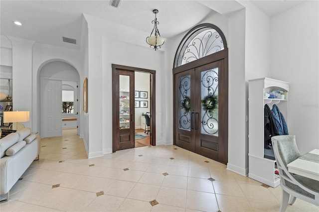 foyer entrance featuring light tile patterned flooring, arched walkways, visible vents, and recessed lighting