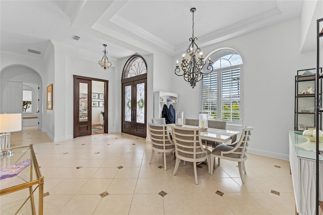 dining area with an inviting chandelier, french doors, light tile patterned flooring, and a raised ceiling