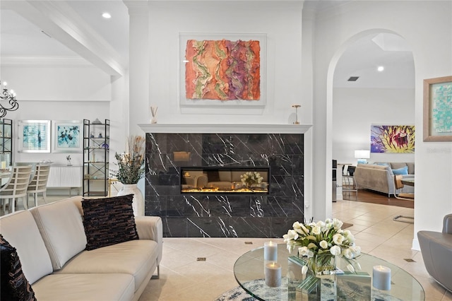 living room with recessed lighting, ornamental molding, tile patterned flooring, arched walkways, and a fireplace