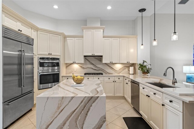 kitchen with a peninsula, appliances with stainless steel finishes, light tile patterned floors, and a sink