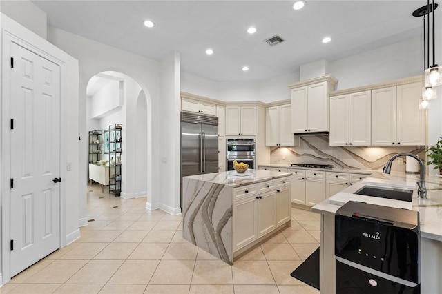 kitchen with light tile patterned floors, a sink, visible vents, arched walkways, and appliances with stainless steel finishes