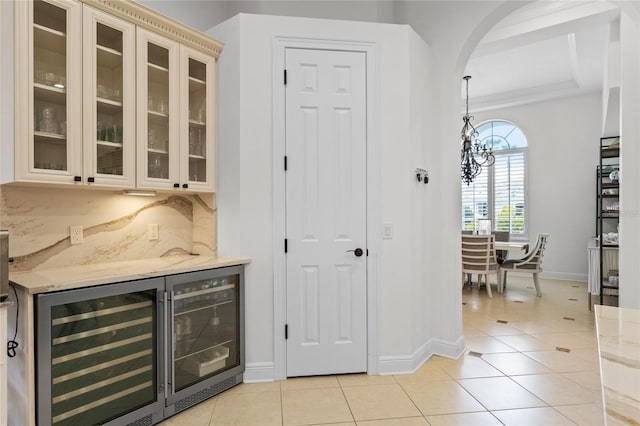 bar with wine cooler, baseboards, light tile patterned floors, an inviting chandelier, and arched walkways