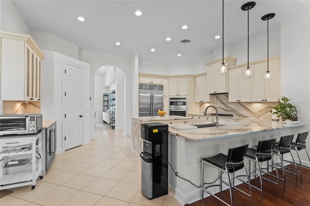kitchen with light stone countertops, a toaster, visible vents, arched walkways, and stainless steel appliances
