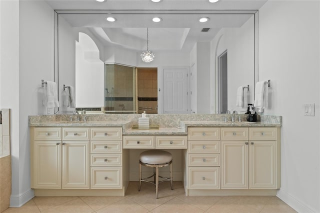 bathroom featuring a tray ceiling, double vanity, visible vents, and tile patterned floors