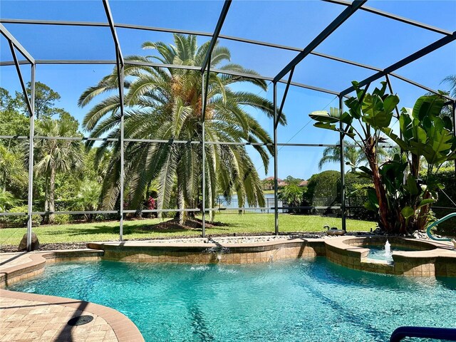 view of swimming pool with a pool with connected hot tub, a lawn, and glass enclosure