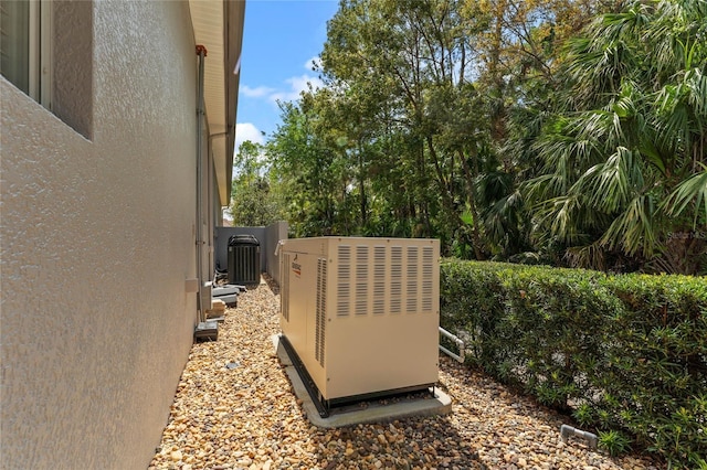 exterior details with a power unit, central AC unit, stucco siding, and fence