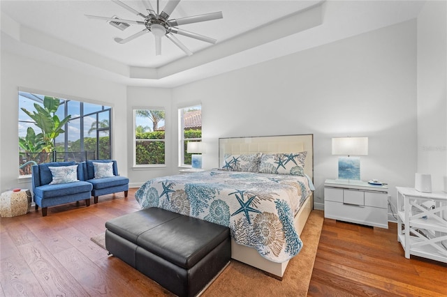 bedroom featuring a ceiling fan, baseboards, a raised ceiling, and hardwood / wood-style flooring