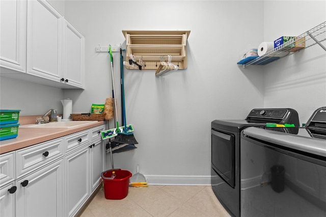clothes washing area with a sink, cabinet space, independent washer and dryer, light tile patterned floors, and baseboards