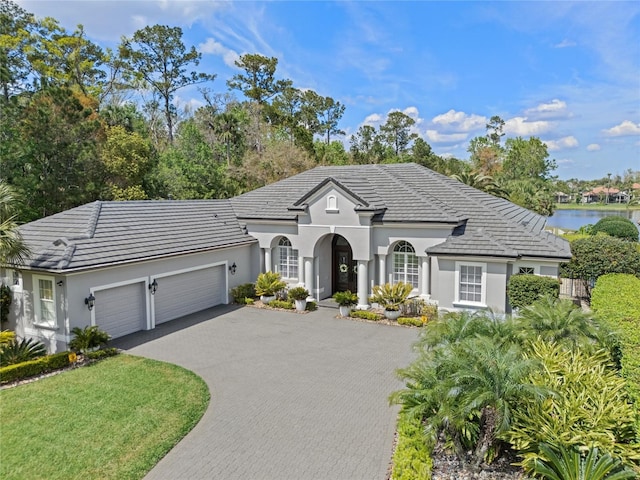 view of front of home featuring a tile roof, an attached garage, stucco siding, and driveway