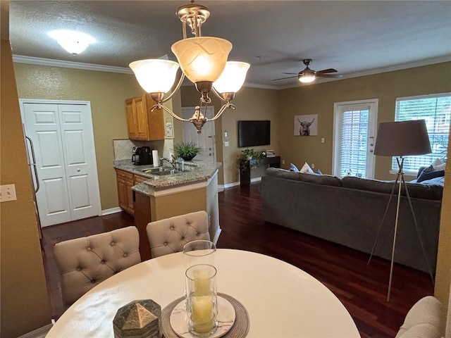 dining area with dark wood-style floors, ceiling fan with notable chandelier, baseboards, and ornamental molding