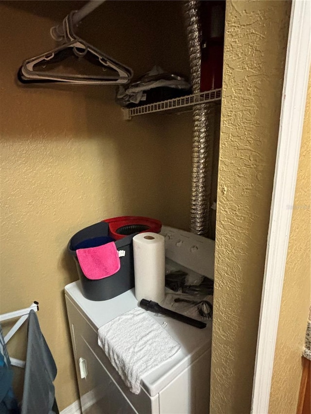 clothes washing area with laundry area and a textured wall