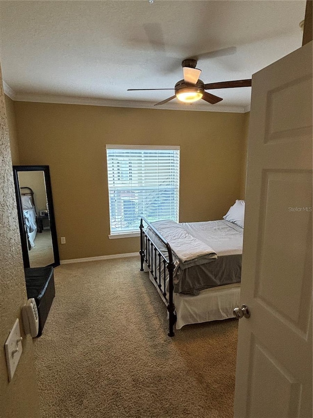 carpeted bedroom featuring a ceiling fan, baseboards, and ornamental molding