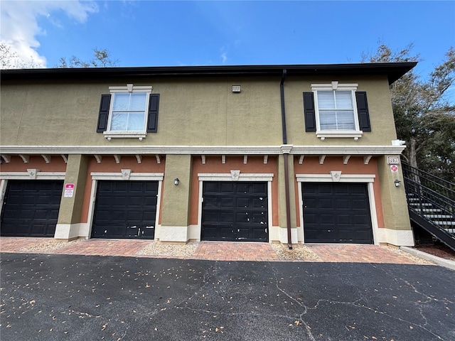 view of front of house featuring stucco siding, driveway, stairs, and a garage