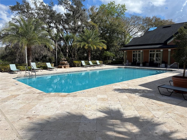 community pool featuring an outdoor structure, a storage structure, and a patio area