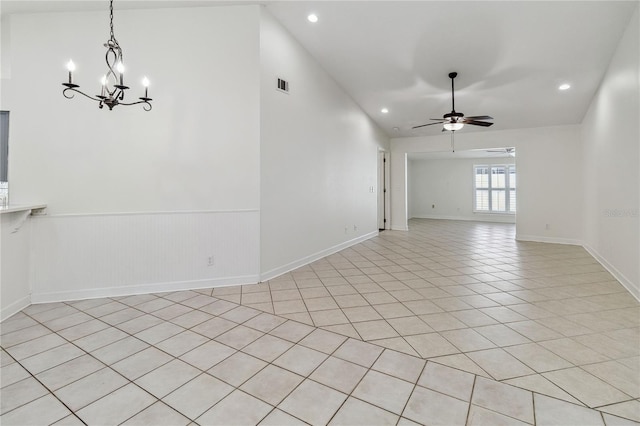 empty room with light tile patterned flooring, wainscoting, visible vents, ceiling fan with notable chandelier, and vaulted ceiling