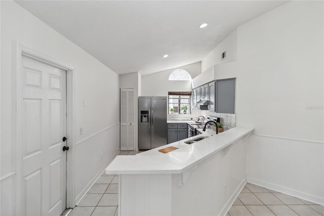 kitchen with gray cabinetry, stainless steel fridge with ice dispenser, light tile patterned floors, and a peninsula