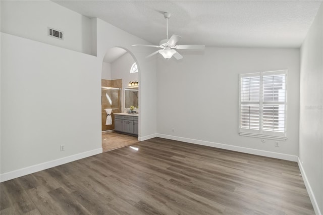 spare room featuring visible vents, lofted ceiling, wood finished floors, ceiling fan, and a textured ceiling