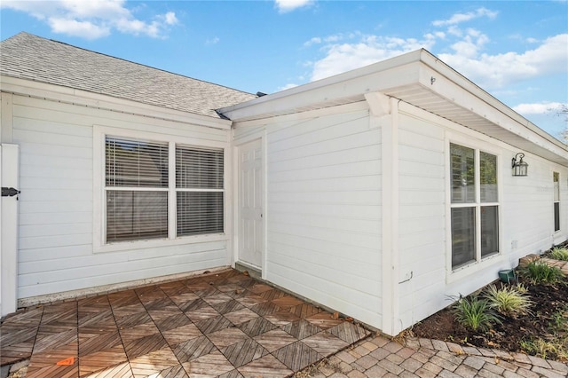 view of side of home with a patio and a shingled roof
