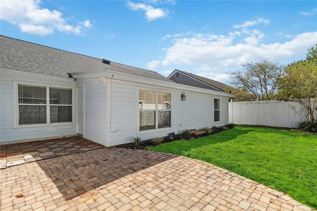 rear view of house featuring fence, a yard, a patio area, and roof with shingles