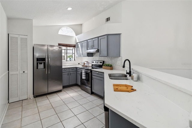 kitchen featuring appliances with stainless steel finishes, a sink, gray cabinets, under cabinet range hood, and visible vents