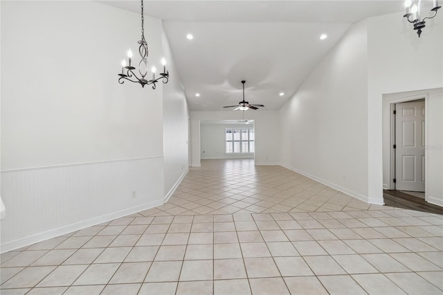 empty room featuring light tile patterned floors, high vaulted ceiling, ceiling fan with notable chandelier, and recessed lighting