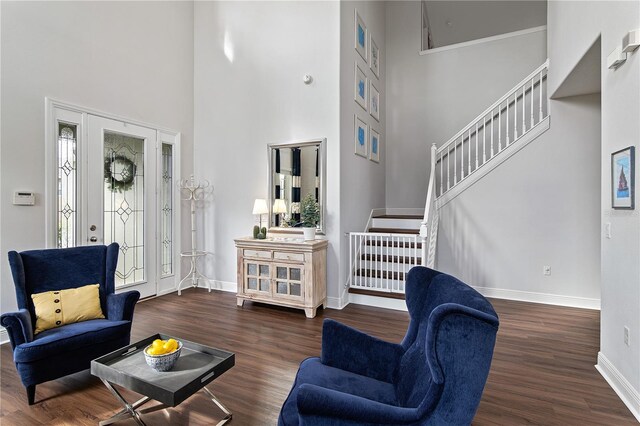 entryway with stairway, a towering ceiling, baseboards, and wood finished floors