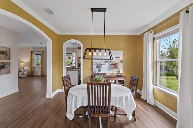 dining space with visible vents, arched walkways, dark wood finished floors, and crown molding