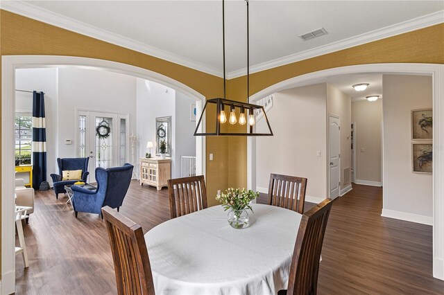 dining space featuring visible vents, a notable chandelier, dark wood finished floors, arched walkways, and crown molding