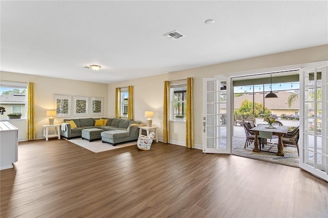 living area featuring dark wood finished floors, visible vents, french doors, and baseboards