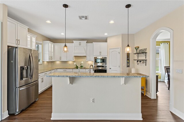 kitchen featuring visible vents, a breakfast bar, appliances with stainless steel finishes, dark wood-style floors, and white cabinetry